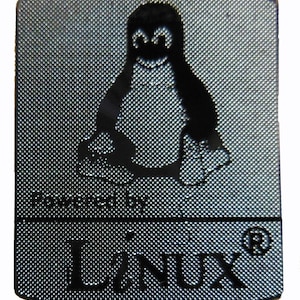 May include: A rectangular, silver-colored metal tag featuring the Linux penguin logo in black. The text "Powered by Linux" and the word "Linux" are also in black. The tag has a textured surface.
