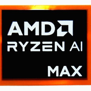 May include: A rectangular sticker with an orange border and a black center. The white text reads "AMD RYZEN AI MAX". The AMD logo is also white. The sticker is likely for a computer component.