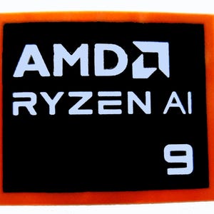 May include: A black rectangular sticker with an orange border. The white text "AMD RYZEN AI 9" is displayed on the sticker, along with the AMD logo. This sticker is likely for a computer component.
