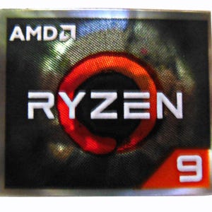 K&ouml;nnte beinhalten: Rechteckiger Aufkleber mit dem wei&szlig;en AMD-Logo, dar&uuml;ber das Wort "RYZEN" in Wei&szlig; und ein rotes kreisf&ouml;rmiges Design in der Mitte. Die Zahl "9" ist wei&szlig; auf orangefarbenem Hintergrund. Der Hintergrund ist schwarz.