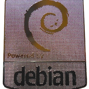 May include: Rectangular metal badge with a perforated surface. The top section features a gold spiral design and the words "Powered by". The bottom section displays the word "debian" in bold black letters.
