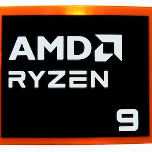 Puede incluir: Un cuadrado negro con un borde naranja muestra el texto blanco "AMD RYZEN" y el número "9". También se ve el logotipo de AMD. Esta imagen probablemente está relacionada con componentes de hardware informático.