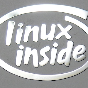 Op de afbeelding: Een zilveren ovale sticker met de tekst "linux inside" in witte letters.