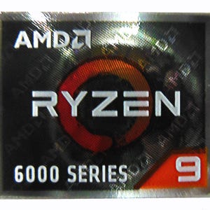 May include: A rectangular sticker with the AMD logo at the top. The word "RYZEN" is in large white letters. Below, it reads "6000 SERIES 9" in white text on a black and orange background. The sticker has a holographic effect.