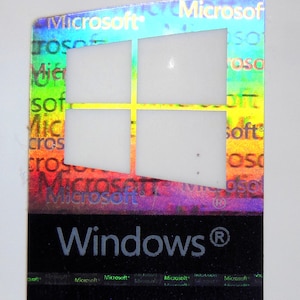 Può includere: Un adesivo olografico con uno schema di colori arcobaleno che presenta il logo di Microsoft Windows e il testo "Microsoft Windows®".