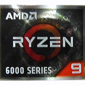 May include: A rectangular sticker with the AMD logo at the top, followed by the word "RYZEN" in white capital letters. Below, it reads "6000 SERIES" and the number "9" in a red box. The background is black with a holographic effect.