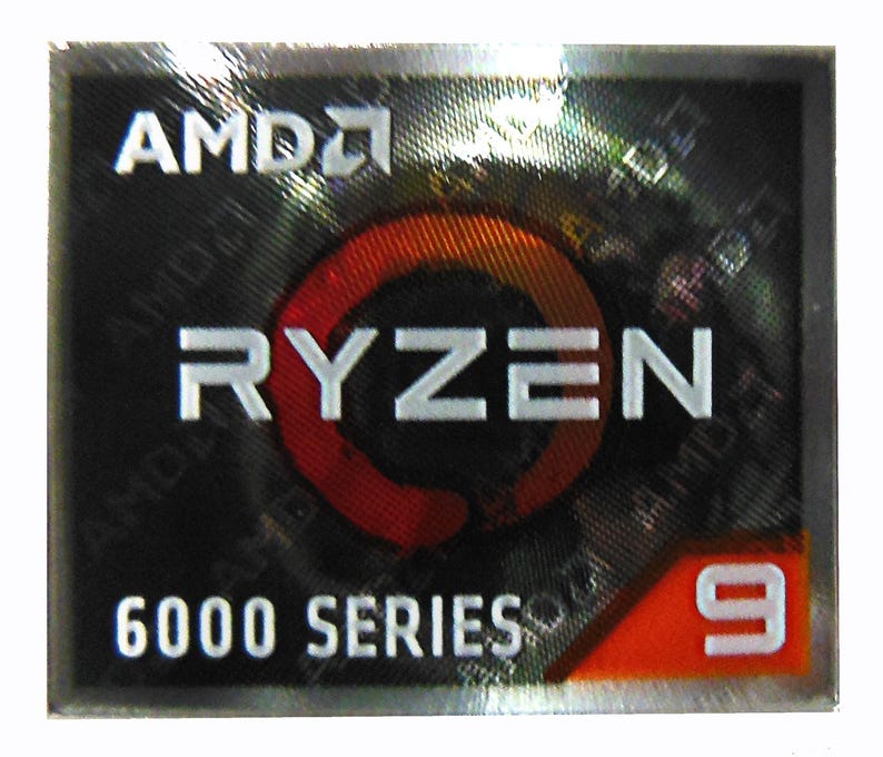 May include: A rectangular sticker with the AMD logo at the top, followed by the word "RYZEN" in white capital letters. Below, it reads "6000 SERIES" and the number "9" in a red box. The background is black with a holographic effect.