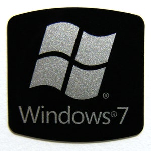 May include: A black sticker with a silver Windows logo and the text "Windows® 7".