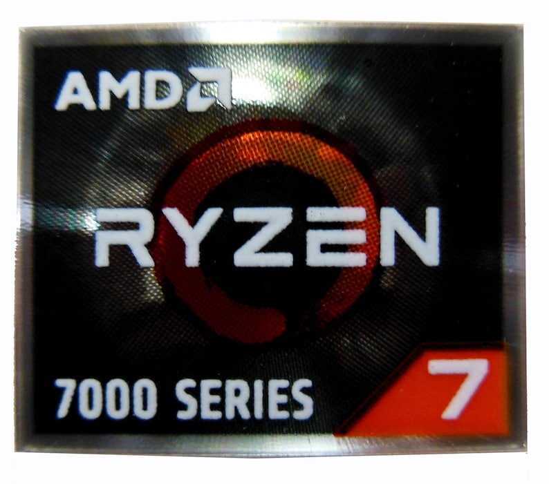 Puede incluir: Una pegatina rectangular con el logotipo de AMD en la parte superior. Debajo, la palabra "RYZEN" en blanco, con un dise&ntilde;o circular rojo y naranja detr&aacute;s. El texto "7000 SERIES" est&aacute; debajo, y el n&uacute;mero "7" en una esquina roja.
