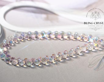 Peut inclure: Un charm de téléphone fait à la main en cristal. Il est composé de perles irisées et facettées roses, violettes et transparentes, enfilées ensemble. Le texte "BRING SPARKLE TO EVERYDAY LIFE" et "BLING CRYSTAL HANDMADE JEWELLERY" sont visibles.