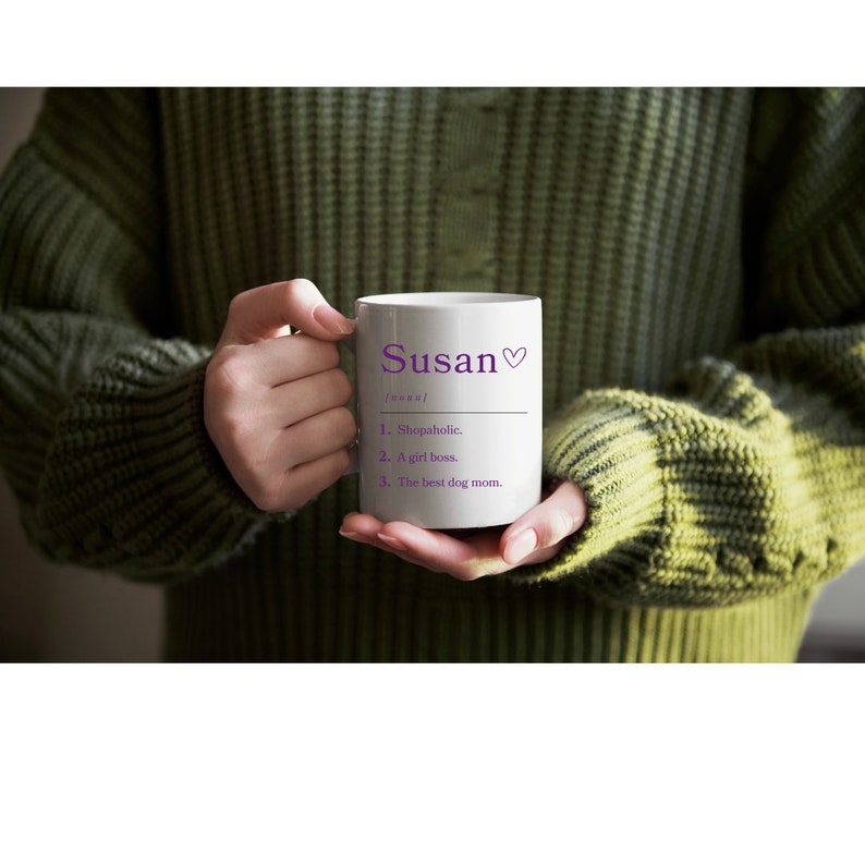 K&ouml;nnte beinhalten: Eine wei&szlig;e Keramiktasse mit einem violetten Design. Die Tasse sagt "Susan" und definiert den Namen als "Shopaholic, A girl boss, The best dog mom."