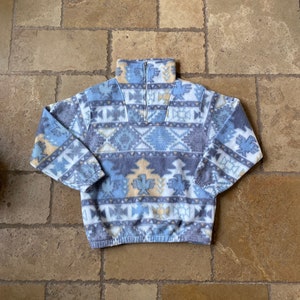 May include: A blue, beige, and white patterned fleece pullover with a half-zip closure.
