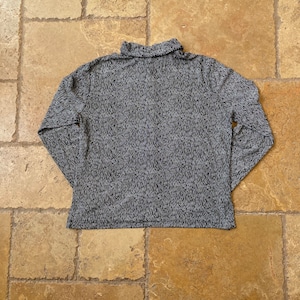K&ouml;nnte beinhalten: Ein lang&auml;rmliges Rollkragen-Shirt mit einem schwarz-wei&szlig;en Muster.