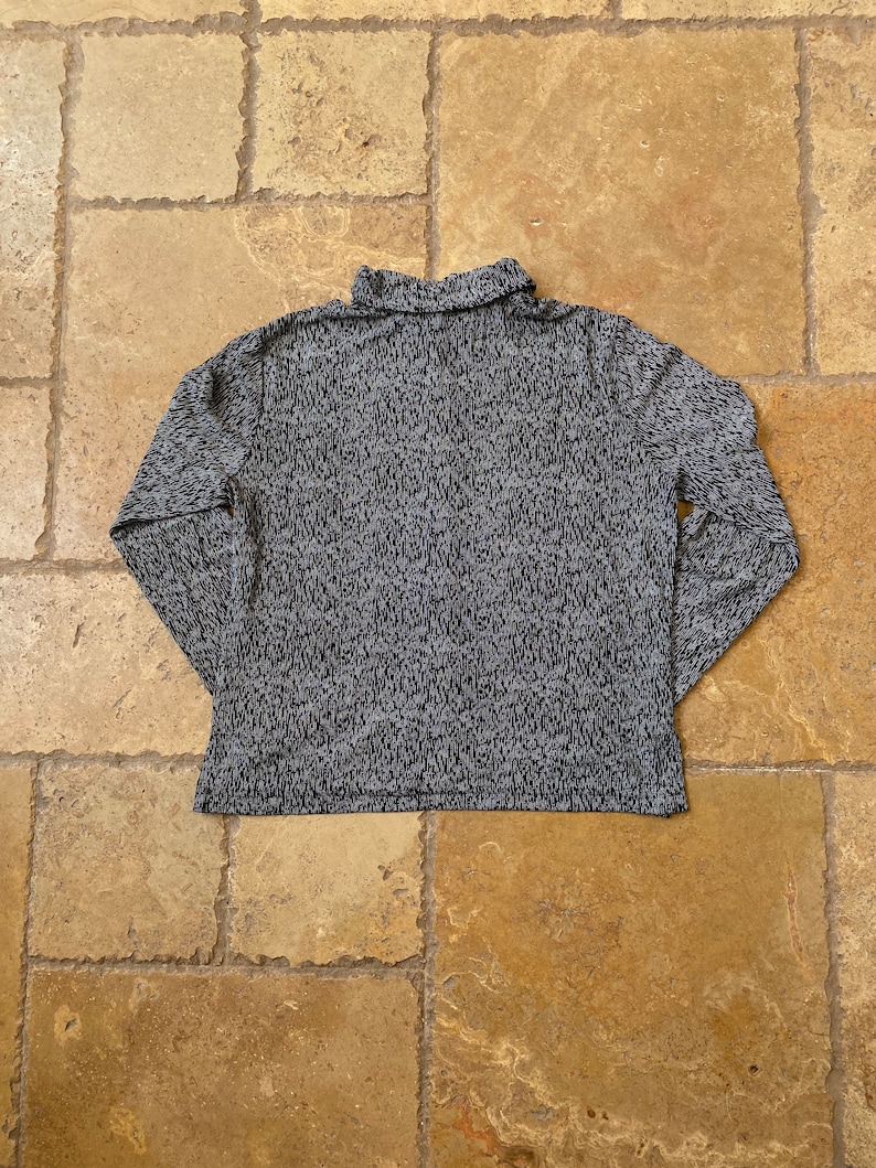 K&ouml;nnte beinhalten: Ein lang&auml;rmliges Rollkragen-Shirt mit einem schwarz-wei&szlig;en Muster.