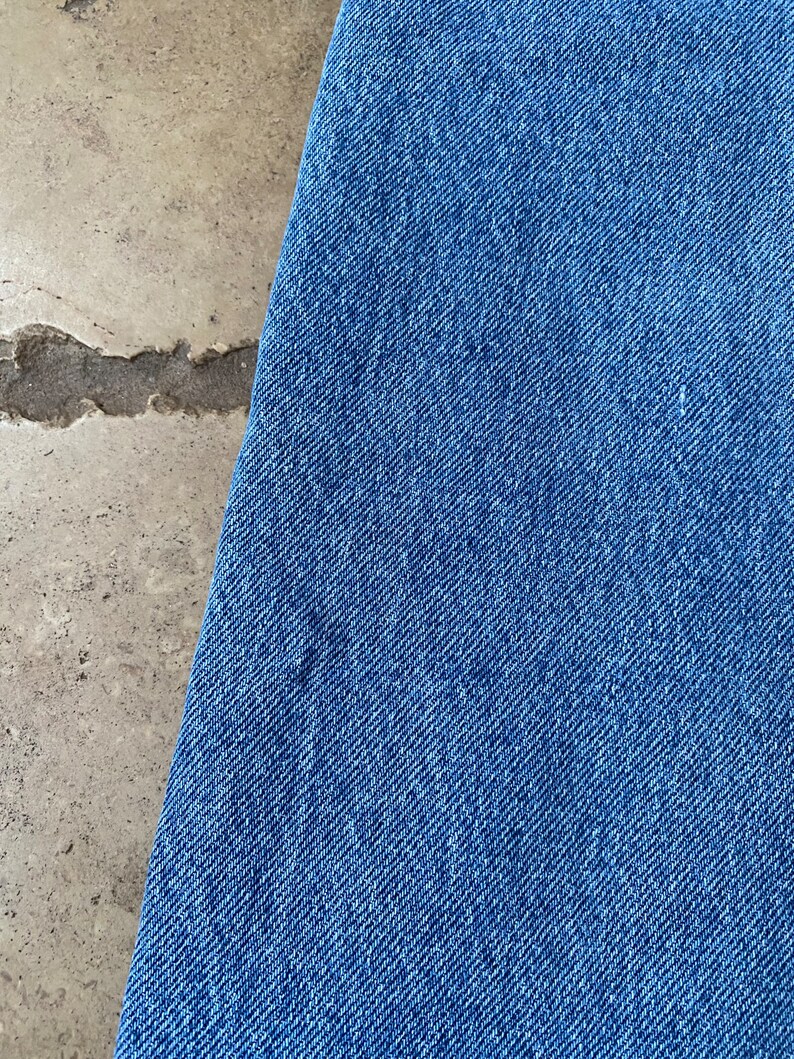 K&ouml;nnte beinhalten: Nahaufnahme eines blauen Jeansstoffes mit diagonalem Webmuster.