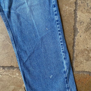 K&ouml;nnte beinhalten: Nahaufnahme des unteren Teils einer blauen Jeans. Der Stoff ist hell gewaschen und die N&auml;hte sind sichtbar.