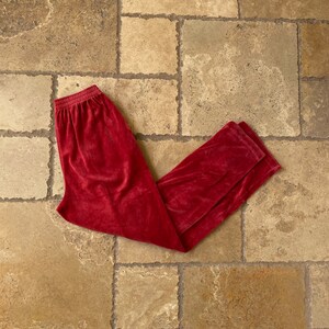May include: A pair of red velour pants. The pants have a wide waistband and a relaxed fit.