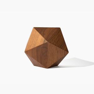 May include: A geometric wooden sculpture with a brown finish. The sculpture is shaped like a diamond with multiple facets.