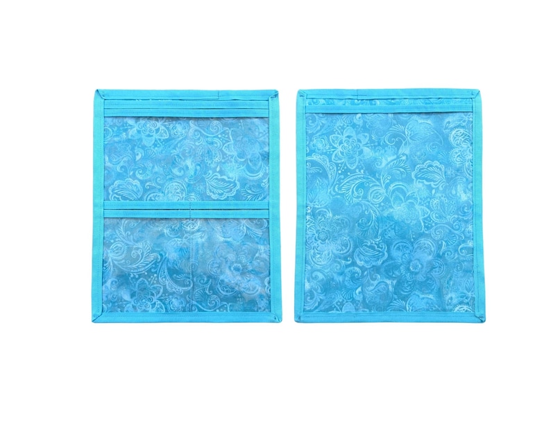 Pu&ograve; includere: Due organizer rettangolari in tessuto blu turchese brillante con un motivo floreale paisley tono su tono. Un organizer presenta due tasche orizzontali in plastica trasparente, l'altro &egrave; una tasca singola aperta, entrambi con bordo blu coordinato.