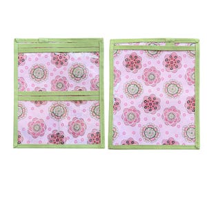 Pu&ograve; includere: Due organizer in tessuto rettangolari con uno sfondo rosa chiaro caratterizzato da un motivo floreale ripetuto nelle tonalit&agrave; del rosa, verde e bianco. Gli organizer sono rifiniti con bordi in tessuto verde chiaro e includono tasche orizzontali.