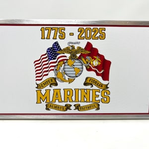May include: Rectangular metal belt buckle with a white background featuring the text "1775-2025" and the word "MARINES" in gold. The design includes the American flag, the Marine Corps emblem, and the words "Semper Fidelis" and "Always Faithful."