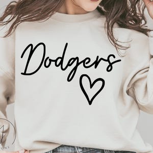 May include: A white sweatshirt with the word "Dodgers" written in black cursive script and a black heart below it.