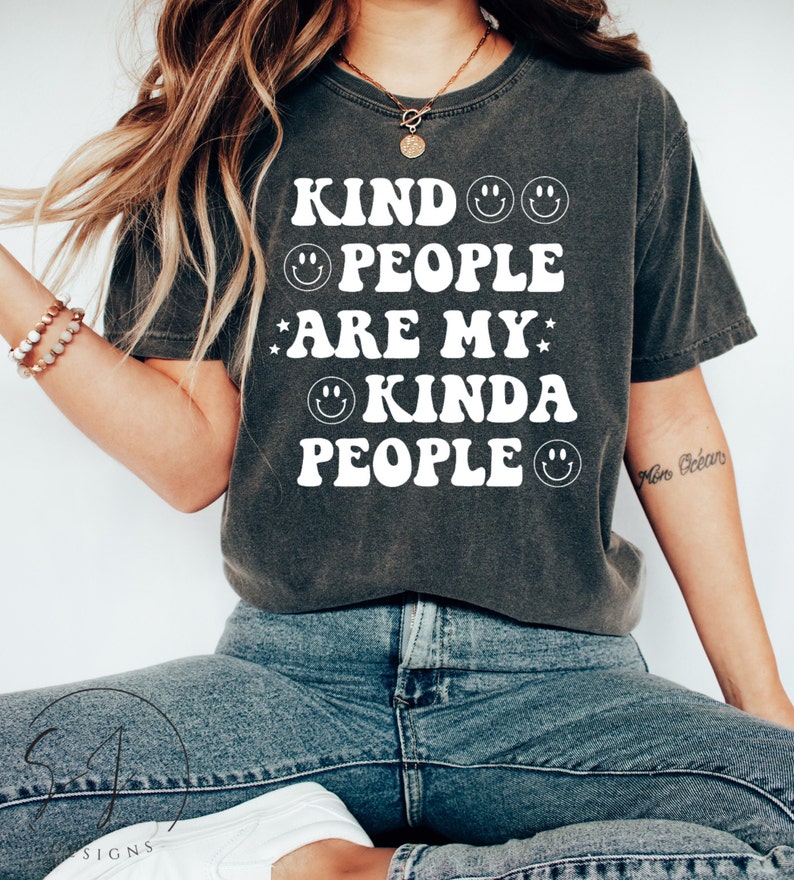 May include: Dark grey t-shirt featuring the white text "KIND PEOPLE ARE MY KINDA PEOPLE", with smiley faces and star graphics. A casual style tee, suitable for everyday wear.