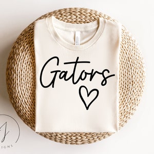 May include: A white t-shirt with the text "Gators" in black script lettering and a black heart underneath.