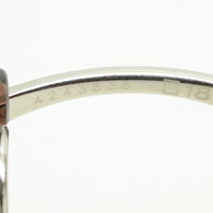 May include: Close-up of the inside of a silver-toned pair of sunglasses with the numbers 4243838 and 18 engraved on the metal arm.