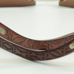May include: Two brown wooden sunglasses frames with a carved floral design. The frames have a silver metal plate with the word 'Carrera' engraved on them.