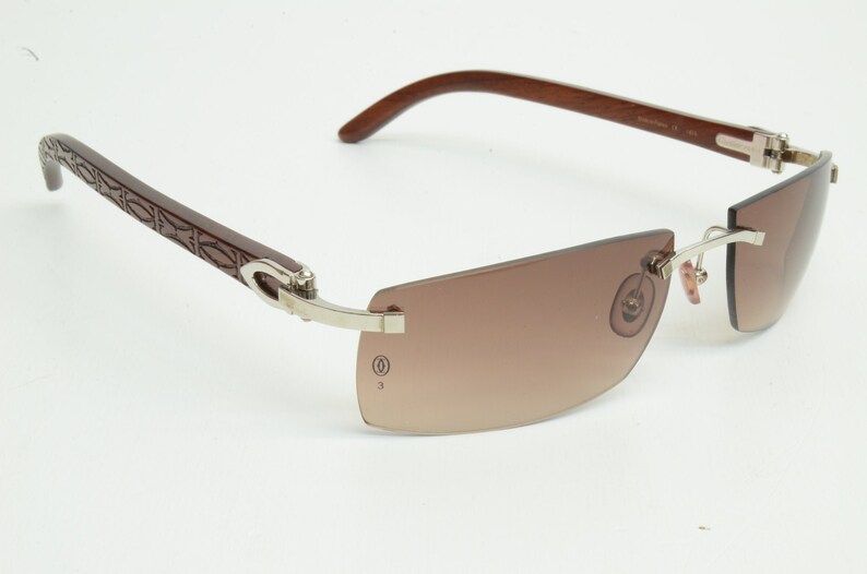 May include: Brown wood-framed sunglasses with silver metal accents and brown gradient lenses.