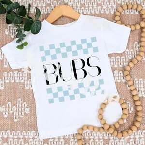 May include: White baby onesie with a blue and white checkered pattern and the word "BUBS" in black letters.