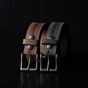 May include: Two leather belts with metal buckles. One belt is brown with a braided design and the other is dark green with a similar braided design.