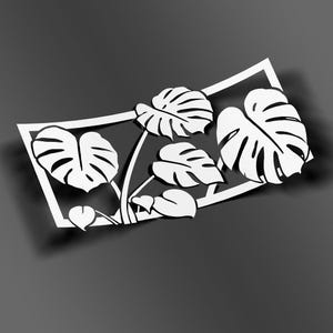 Può includere: Silhouette bianca di una pianta di monstera con foglie in una cornice quadrata. Le foglie sono grandi e hanno una forma distintiva con dei buchi.