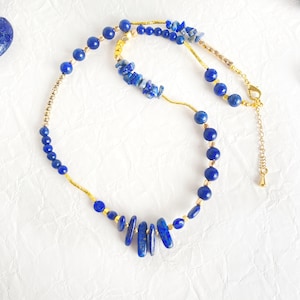 Könnte beinhalten: Eine goldene und blaue Halskette mit Lapislazuli-Perlen und -Steinen. Die Halskette hat ein langes, baumelndes Stück Lapislazuli.