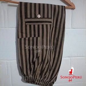 May include: Brown and beige striped pants with a button and a pocket. The pants have a drawstring at the bottom. The pants are hanging on a wooden hanger. The text "SONQO PER&Uacute; Art" is visible in the bottom right corner of the image.