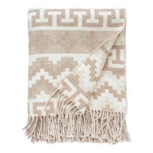 May include: A beige and white throw blanket with a geometric pattern and fringe. The blanket is folded in half and has a tassel fringe.