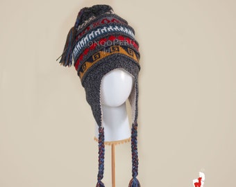 May include: Gray knitted hat with a colorful geometric pattern and long braided tassels. The hat has ear flaps and a pom-pom on top.