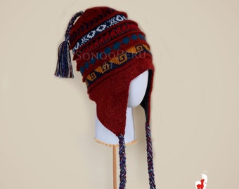 May include: A red knitted hat with a colorful geometric pattern and long braided tassels. The hat has ear flaps and a pom-pom on top.