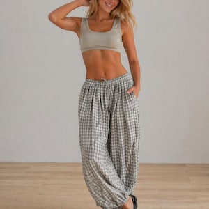 May include: A woman wearing a light green crop top and gray and white checkered pants. The pants have a drawstring waist and are gathered at the ankles. She is wearing black sandals.