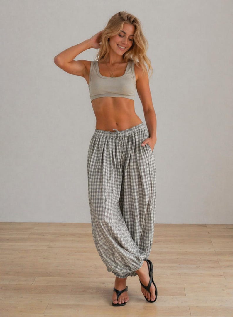 May include: A woman wearing a light green crop top and gray and white checkered pants. The pants have a drawstring waist and are gathered at the ankles. She is wearing black sandals.