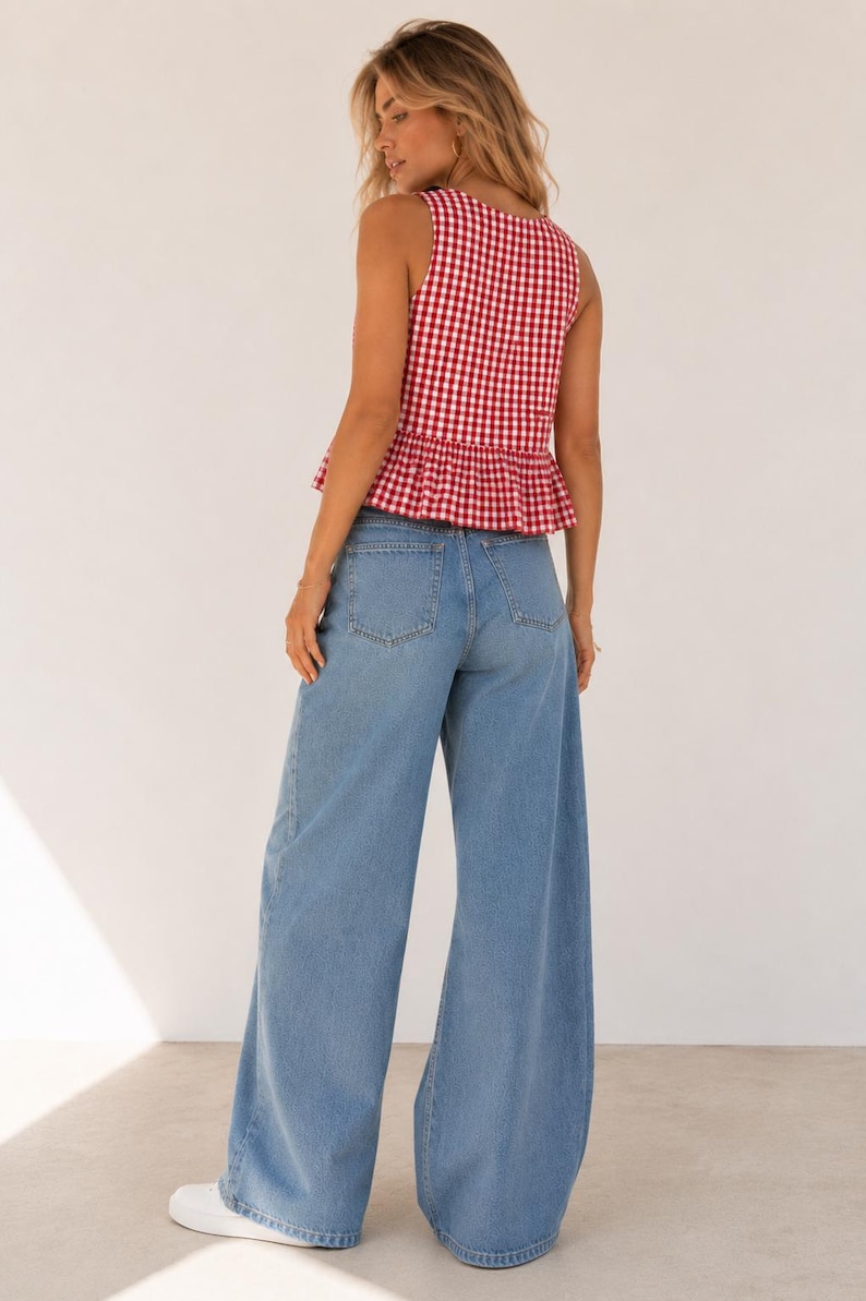 May include: A sleeveless red and white gingham peplum top paired with light blue wide-leg denim jeans and white sneakers. The top features a square neckline and a ruffled hem, while the jeans have a classic five-pocket design and a loose fit.