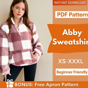 以下が含まれることがあります： バーガンディと白のチェック柄のAbbyスウェットシャツ。ハーフジップの襟とフロントポケットが付いています。画像には「PDF Pattern」、「Abby Sweatshirt」、「XS-XXXL」、「Beginner Friendly」という文字も含まれています。