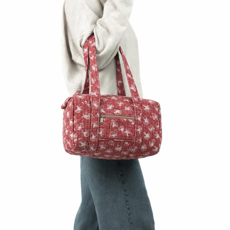 Pu&ograve; includere: Una borsa da viaggio trapuntata rossa con un motivo floreale bianco. La borsa ha due manici e una tasca frontale con cerniera. La borsa misura circa 25 cm di altezza, 46 cm di larghezza e 25 cm di profondit&agrave;.