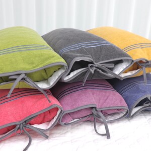 May include: Six decorative pillows with different colored fabric covers and gray trim. Each pillow has a white lining and a gray ribbon tied around the center.