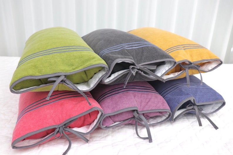 May include: Six decorative pillows with different colored fabric covers and gray trim. Each pillow has a white lining and a gray ribbon tied around the center.