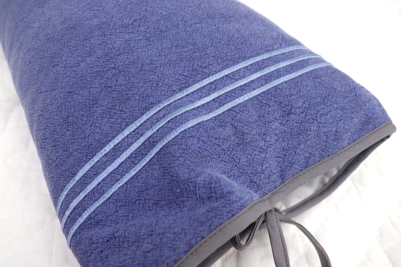 May include: A blue fabric pouch with a drawstring closure and two white stitching lines. The pouch is made of a textured fabric.