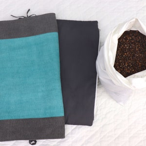 May include: Two fabric pillow covers, one teal blue with gray trim and one gray, and a white bag filled with brown buckwheat hulls.