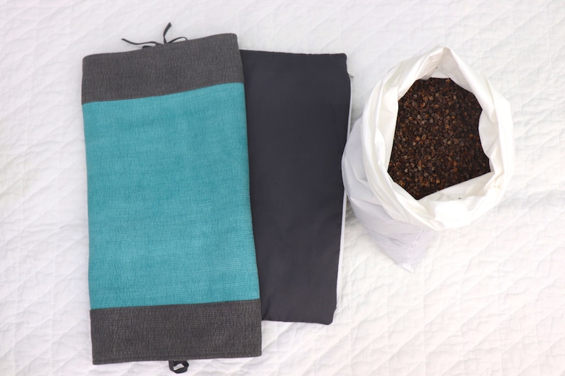 May include: Two fabric pillow covers, one teal blue with gray trim and one gray, and a white bag filled with brown buckwheat hulls.