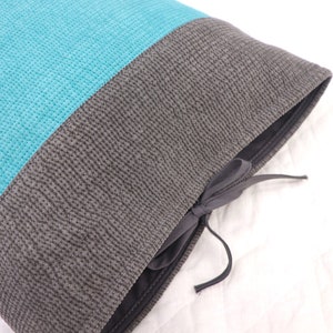 May include: A turquoise and gray pillow with a drawstring closure. The pillow is made of a soft, textured fabric.